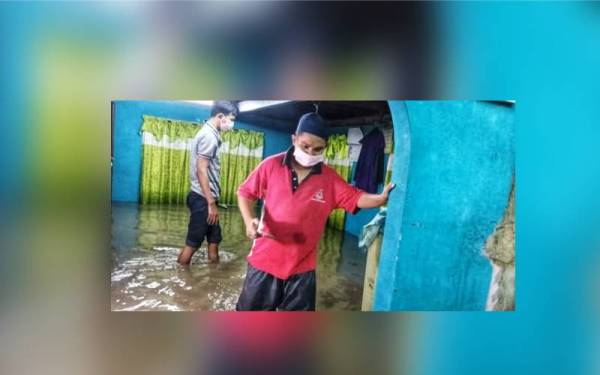 Muhammad Rizuwan mengharungi air yang memenuhi ruang rumahnya dalam kejadian air pasang besar di pesisiran pantai Kuala Kedah.