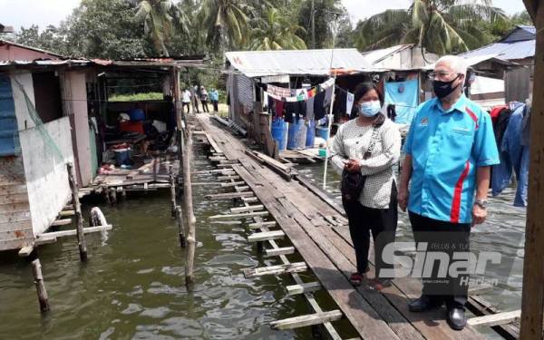 Hassan (kanan) melawat rumah Noraisyah (kiri) dan meninjau keadaan titi yang sudah usang serta reput di Kampung Orang Asli Teluk Jawa, Pasir Gudang pada Sabtu.