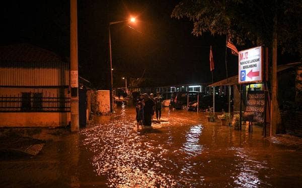 Sebahagian penduduk di Jalan Kuala Kedah keluar dari kawasan perumahan mereka selepas kediaman mereka dinaiki air pada awal pagi tadi berikutan berlakunya fenomena air pasang besar. - Foto Bernama