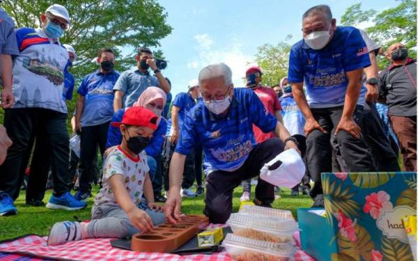 Ismail Sabri mencuba permainan congkak bersama seorang kanak-kanak selepas melancarkan sambutan Bulan Keluarga Malaysia (BKM) di Taman Botani Perdana pada Ahad. - Foto Bernama