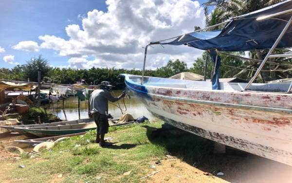 Mustaqim mengambil upah mengecat dan membaik pulih bot semasa nelayan ‘bercuti’ daripada turun ke laut pada musim tengkujuh.