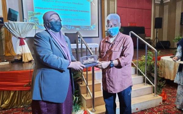 Dr Nor Azimi (kiri) menyampaikan cenderahati kepada Presiden Kelab Media Pahang, Datuk Nik Naizi Husin pada majlis bersama media di Hotel Grand Makmur, Kuantan pada Isnin.