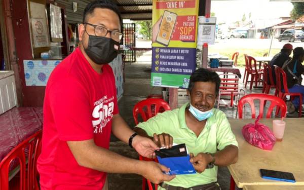 Kru Rasuah Busters mengedarkan pelitup muka khas yang menjadi sebahagian kempen memerangi rasuah kepada Mohd Azamli Mat Zain.