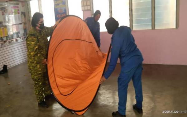 Anggota APM daerah Kota Setar mengemas dan melipat collabsible tent di SK Convent, Alor Setar selepas mangsa banjir pulang ke rumah masing-masing. - Foto APM Kota Setar