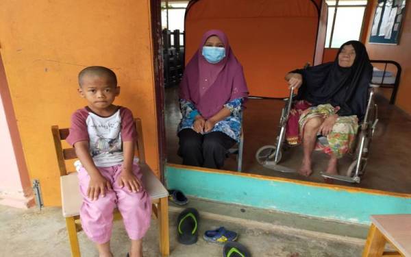 Noraini (tengah) bersama ibu mentua, Wan Miah,80 dan anaknya Afiq Udin Shukri, 8 di PPS SK Malau.