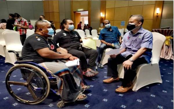 Fuad (kanan) beramah mesra dengan OKU yang menghadiri sesi temuduga. 