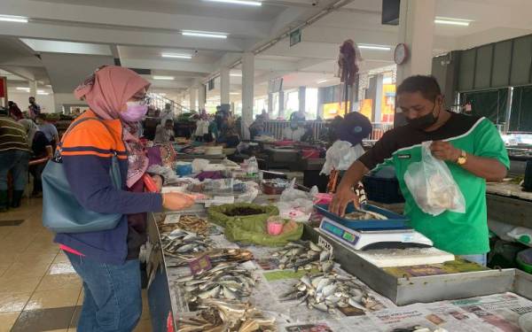 Ikan kering yang dijual Nik Azmi (kanan) di Pasar Cabang Tiga, Pengkalan Chepa sering mendapat permintaan ramai di musim tengkujuh.