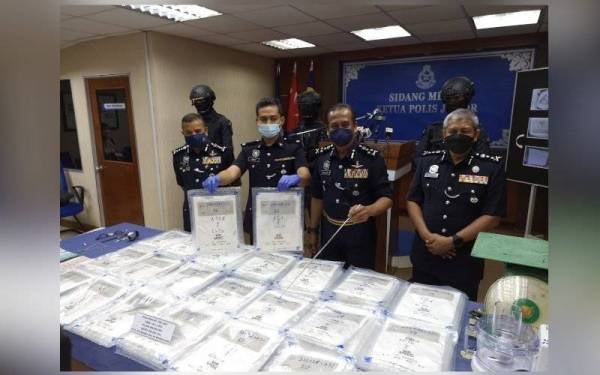 Razarudin ( kanan) menunjukkan rampasan heroin sindiket dadah antarabangsa pada sidang akhbar di IPK Johor pada Khamis.