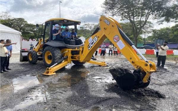 Fadillah (tengah) menyempurnakan gimik pecah tanah untuk kerja menaik taraf Jalan FT050, Jalan Batu Pahat-Ayer Hitam-Kluang di Ayer Hitam pada Khamis. Turut sama, Ka Siong. - Foto Bernama 