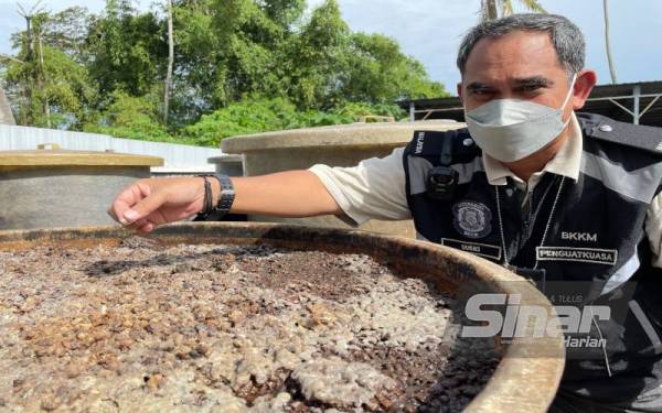 Mohd Wazir menunjukkan bahan asing iaitu bulu burung yang ditemui di dalam bekas gentian kaca di kilang kicap di Bagan Ajam.