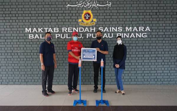 Wakil Bank Rakyat (dua dari kanan) menyerahkan pensanitasi tangan berpedal kepada penerima yang mewakili Maktab Rendah Sains Mara Balik Pulau, Pulau Pinang (dua dari kiri) sempena pembukaan sekolah.
