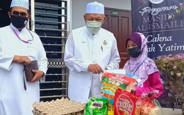Ahmad (tengah) menyampaikan sumbangan kepada seorang anak yatim semasa merasmikan Wisma Ilmu dan Pelancaran Program Anak Yatim di Masjid Al-Ismaili Mukim Morak di Tumpat pada Jumaat.