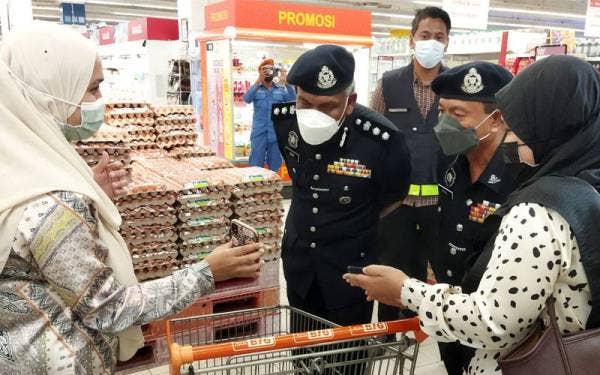Wan Mohd Zahari (dua dari kiri) melakukan pemeriksaan ke atas pelanggan pasar raya dalam sebuah pusat beli belah di bandar Kuantan pada Jumaat.