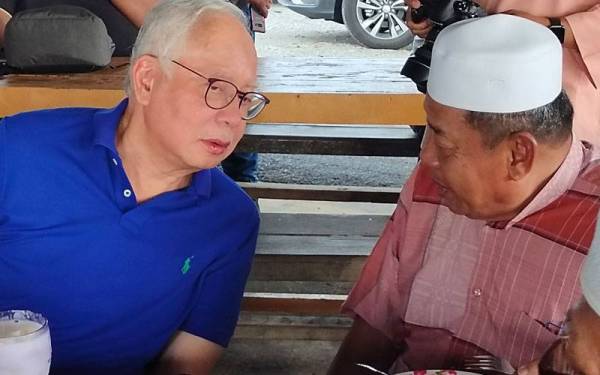 Najib (kiri) bersembang santai bersama penduduk Kampung Balik Batu, Masjid Tanah pada Jumaat.