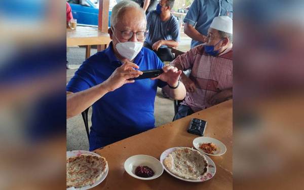 Najib sempat merakamkan gambar lempeng kelapa yang dihidangkan menggunakan telefon bimbitnya sebelum menjamu selera.