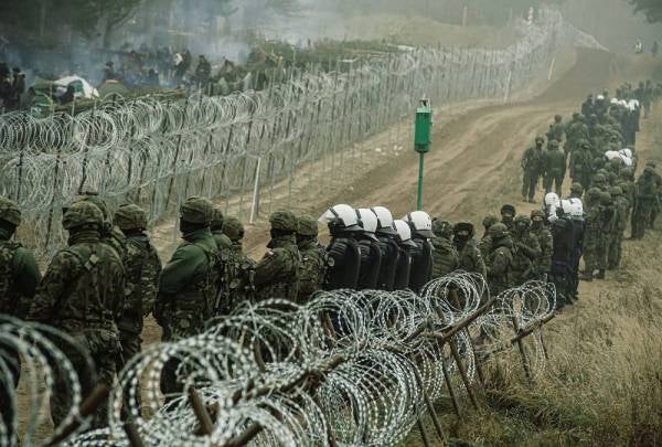 A handout photo made available by Polish Territorial Defence Force shows Polish soldiers, police forces and border guard officers guard the fence during 'Operation Strong Support' near the Polish-Belarusian border crossing in Kuznica, eastern Poland, Nov 11, 2021. According to Polish Border Guard, over a thousand refugees, who want to obtain asylum in the European Union have been trapped at low temperatures at the border Polish-Belarusian border. (Photo by EPA)