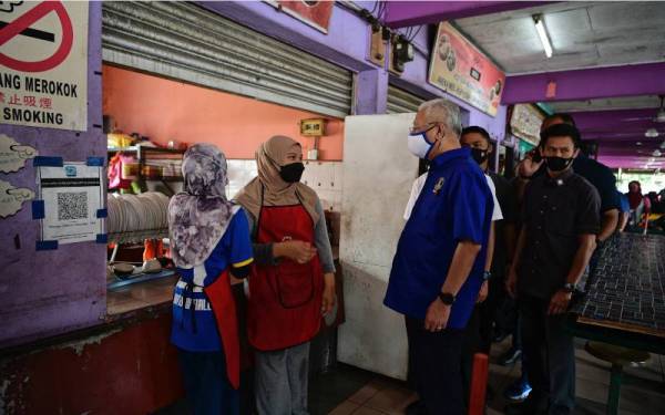 Ismail Sabri (dua, kanan) bertanyakan khabar kepada sebahagian peniaga ketika melakukan lawatan di Medan Selera Asahan pada Ahad. - Foto Bernama 