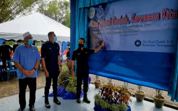 Datuk Rohaimi (kanan) memasang Banner Op Jihad Dadah 2.0 Marang, di Balai Raya Kampung Bukit Gasing, Marang, pada Ahad