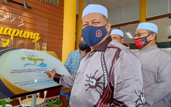 Mohd Amar menandatangani plak perasmian pembukaan Restoran D' Terapung Pantai Sri Tujuh, Tumpat pada Isnin.