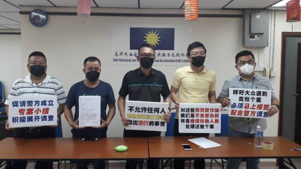 Ah Kit (dua dari kiri) dan Thow Siang (tengah) menunjukkan laporan polis serta sepanduk mahukan pihak polis Johor dan polis Singapura bekerjasama membanteras kegiatan ah long Singapura selepas sidang akhbar di Pejabat MCA Pasir Gudang, Johor Jaya, Johor Bahru pada Selasa.