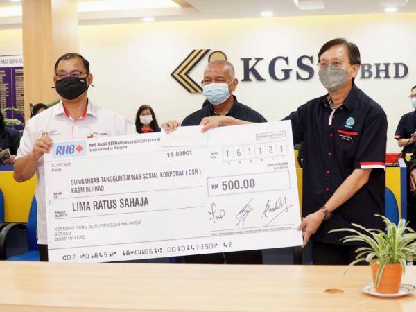 Mohd Suhaimi (kiri) menyampaikan cek RM500 sumbangan KGMB kepada sekolah terpilih.
