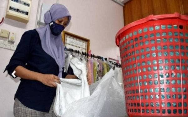 Farah Rahimah memerika pakaian yang dihantar pelanggan untuk dicuci. - Foto Bernama