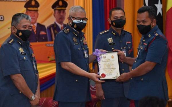 Mohammad Hamdan (dua, kiri) menyampaikan Anugerah Perkhidmatan Cemerlang (APC) kepada anggota JBPM Terengganu, Mohd Aidil Khairim Abd Wahab di Akademi Bomba dan Penyelamat Wilayah Timur, Wakaf Tapai pada Khamis. - Foto Bernama