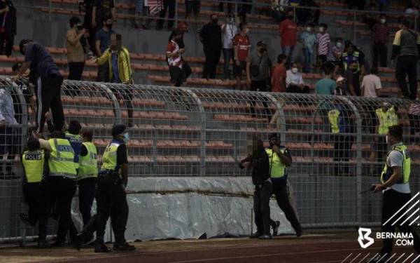 Polis menahan penyokong Kuala Lumpur City FC yang merempuh masuk ke padang ketika meraikan kemenangan selepas menewaskan Selangor FC pada suku akhir kedua Piala Malaysia 2021 di Stadium Kuala Lumpur hari ini. - Foto Bernama