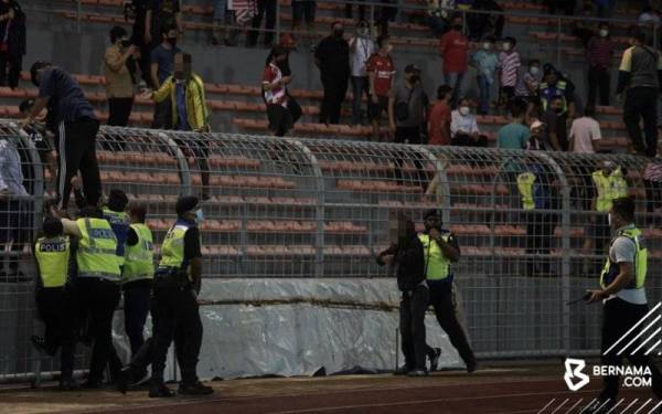 Polis menahan penyokong Kuala Lumpur City FC yang merempuh masuk ke padang ketika meraikan kemenangan selepas menewaskan Selangor FC pada suku akhir kedua Piala Malaysia 2021 di Stadium Kuala Lumpur hari ini. - Foto Bernama
