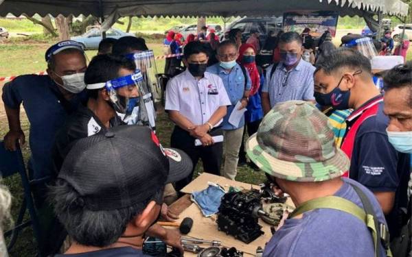 Abdullah (tengah) melihat nelayan yang didedahkan dengan kaedah
penyelenggaraan enjin bot daerah Kuantan di Pantai Sepat di sini.