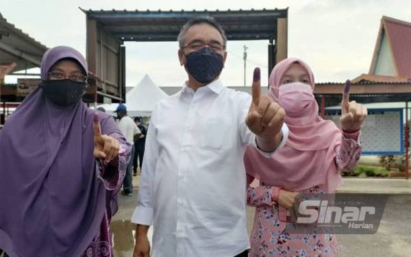 Calon Pakatan Harapan (PH) bagi Dewan Undangan Negeri (DUN) N17 Bukit Katil Adly Zahari (tengah, isteri dan anaknya menunjukkan jari selepas mengundi di Pusat Mengundi SK Durian Tunggal, pada Sabtu.
