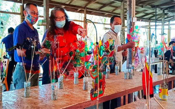 Swee Tin (tengah) melihat patung wayang kulit yang diperbuat daripada plastik buangan semasa bengkel membuat patung wayang kulit plastik anjuran Balai Seni Visual Negara dengan kerjasama Persatuan Wayang Kulit Sri Cindayu di Kubang Kerian, Kota Bharu pada Sabtu.