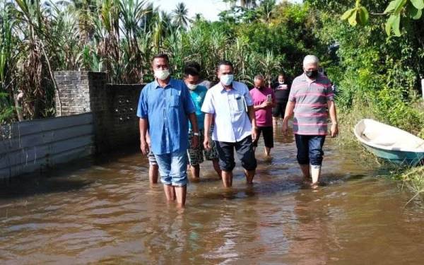 Azli (kiri) bersama Johari (tengah) semasa turun padang melihat kawasan sawah padi yang ditenggelami banjir termenung di Rantau Panjang pada Ahad.