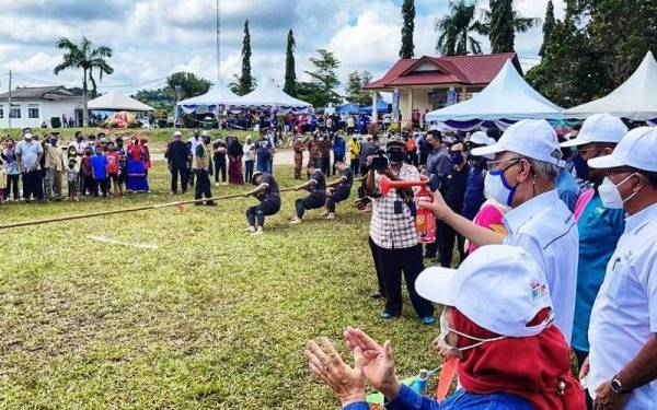 Ismail Sabri (dua dari kiri) merasmikan acara tarik tali sempena Program Merakyatkan Seni Budaya Komuniti Keluarga Malaysia'Hogoh Bera' 2021 di padang Felda Kumai di Bera pada Ahad