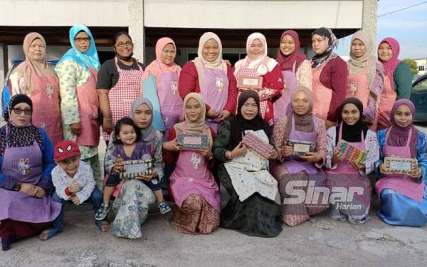 Erni Yulina (duduk, empat dari kanan) bersama pekerjanya menunjukkan produk yang dihasilkan mereka.
