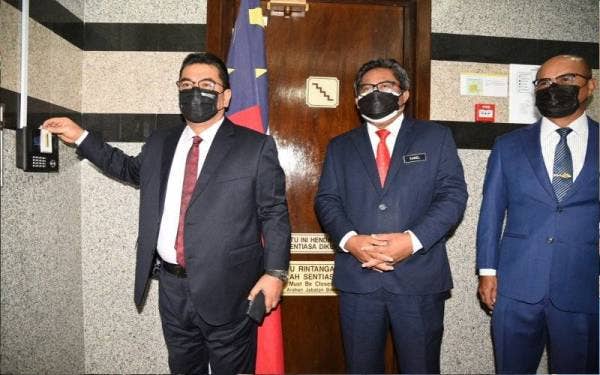 Sulaiman (kiri) mengimbas kad perakam waktu pada hari pertama beliau bertugas sebagai Ketua Menteri di Seri Negeri, Ayer Keroh pada Isnin.