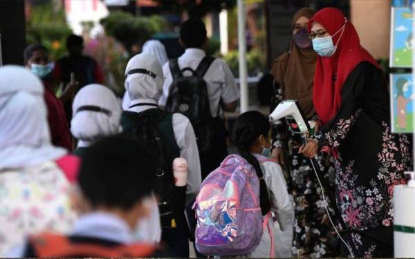 Guru Sekolah Kebangsaan Seberang Jaya di sini mengambil suhu badan murid-murid setibanya mereka ke sekolah bagi memulakan sesi persekolahan hari ini. - Foto Bernama