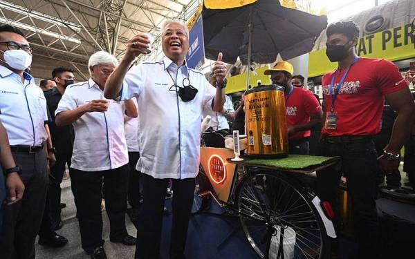 Perdana Menteri Datuk Seri Ismail Sabri Yaakob (tengah) menunjukkan tanda bagus ketika mencuba teh tarik ketika melawat gerai peniaga selepas melancarkan Pas Keluarga Malaysia di KL Sentral hari ini.