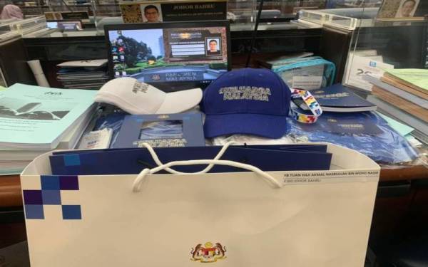 Akmal Nasrullah memuat naik cenderamata Keluarga Malaysia yang diletakkan di atas meja ahli Parlimen di Dewan Rakyat pada Selasa.