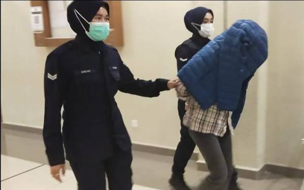 Tertuduh diiringi anggota polis keluar dari Mahkamah Sesyen selepas selesai sebutan kesnya pada Rabu.