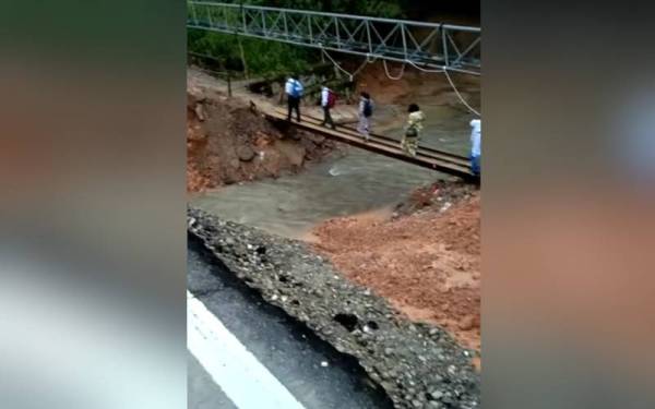 Tular gambar pelajar sekolah melalui jejantas yang menghubungkan laluan Keningau-Tambunan, berhampiran Kampung Liau, yang terputus akibat tanah runtuh pada 9 November lalu.