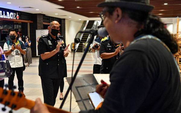 Ketua Polis Perak Datuk Mior Faridalathrash Wahid (dua,kiri) melihat persembahan ‘busking’ ketika hadir pada program Kempen Pencegahan Jenayah Komersial Atas Talian Kontinjen Perak Tahun 2021 di Pusat Beli Belah Aeon Kinta City hari ini.