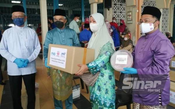 Mohd Daud (dua dari kiri) menyampaikan bakul makanan kepada penerima di Masjid Azzubair Ibnu Awwam, Cheras pada Jumaat.