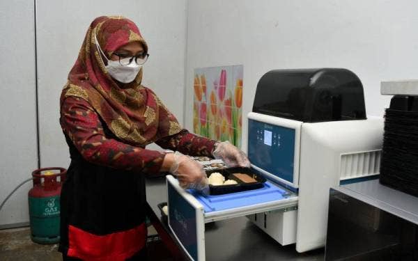 Noryati melakukan proses pembungkusan kuih bekang semasa ditemui di premisnya di Kuala Ibai. - Foto Bernama