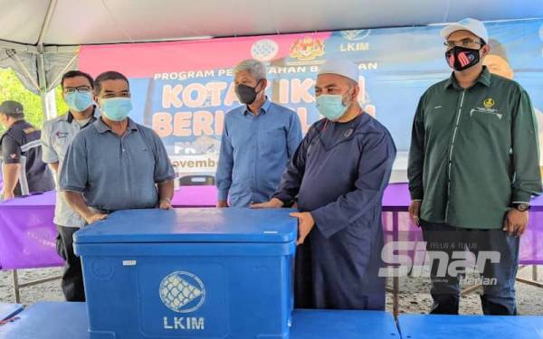 Syed Abu Hussin Hafiz (dua dari kanan) menyerahkan kotak ikan berinsulasi kepada nelayan di Jeti Sungai Kelubong, Bukit Gantang pada Sabtu.