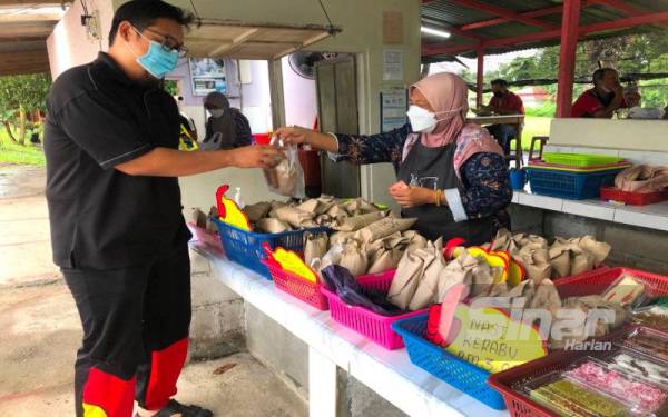 Zarini sedang melayan Syed Abdul Qadir yang membeli nasi bungkus di kedainya. - Foto Sinar Harian