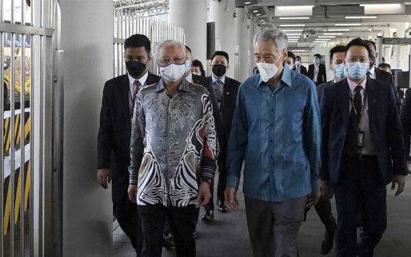 Perdana Menteri, Datuk Seri Ismail Sabri Yaakob (dua dari kiri) disambut rakan sejawatnya Lee Hsien Loong dari Singapura ketika Pelancaran Pengembara Laluan Perjalanan Lengkap Vaksin (VTL) di Woodlands Checkpoint pada Isnin. - Foto Bernama