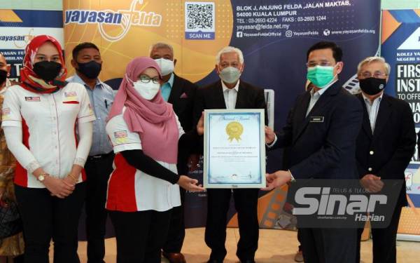Mohd Banuri (kanan) menerima sijil The Malaysia Book Of Records (MBOR) dari Perunding Kanan (Rekod) MBOR, Siti Hajar (dua dari kiri) disaksikan oleh Pengerusi FELDA, Datuk Seri Idris Jusoh (tengah) ketika majlis Penyerahan Malaysia Book Of Records kepada Yayasan Felda.- Foto Sinar Harian ROSLI TALIB