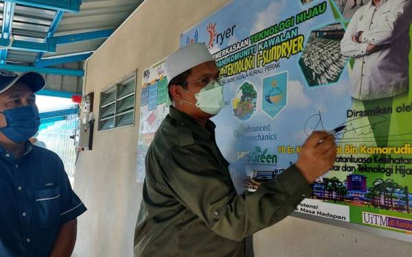 Mohd Akmal menandatangani papan tanda simbolik merasmikan Rumah Pengeringan Solar Pintar inisiatif kerajaan negeri dengan usahasama UiTM.