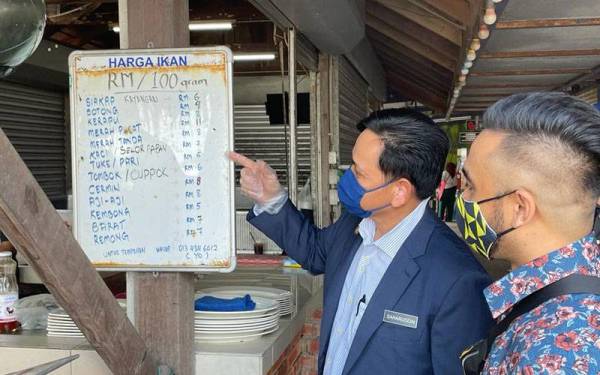 Saharuddin (kiri) sedang memeriksa harga yang dipamerkan kepada pengguna di salah sebuah restoran di sekitar Kuala Terengganu.